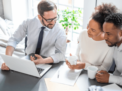 A couple buying insurance to an insurance agent and the agent explains the benefits of buying insurance in a local agent vs online