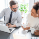 A couple buying insurance to an insurance agent and the agent explains the benefits of buying insurance in a local agent vs online