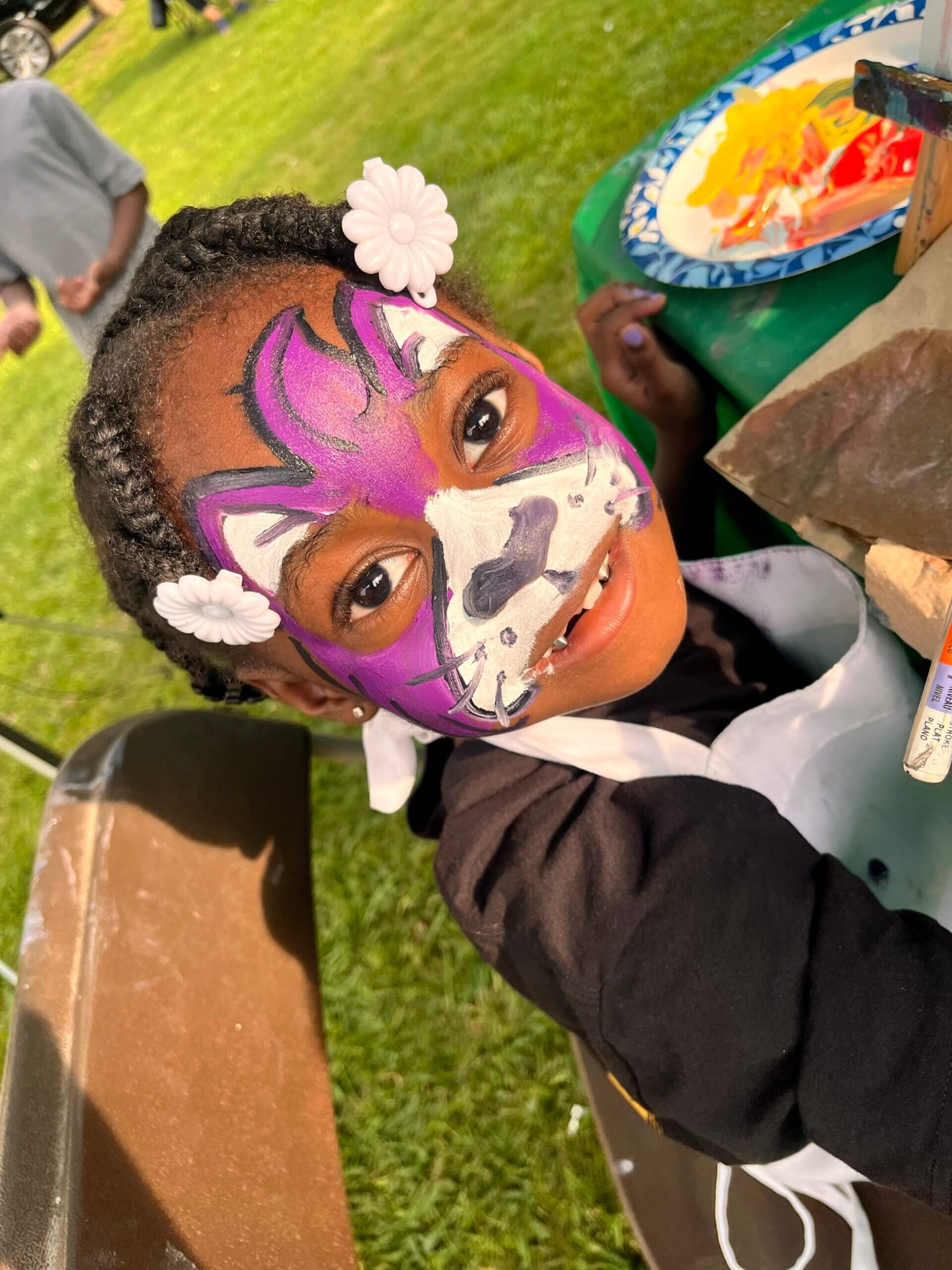 Child with face painting panther color violet in the festival