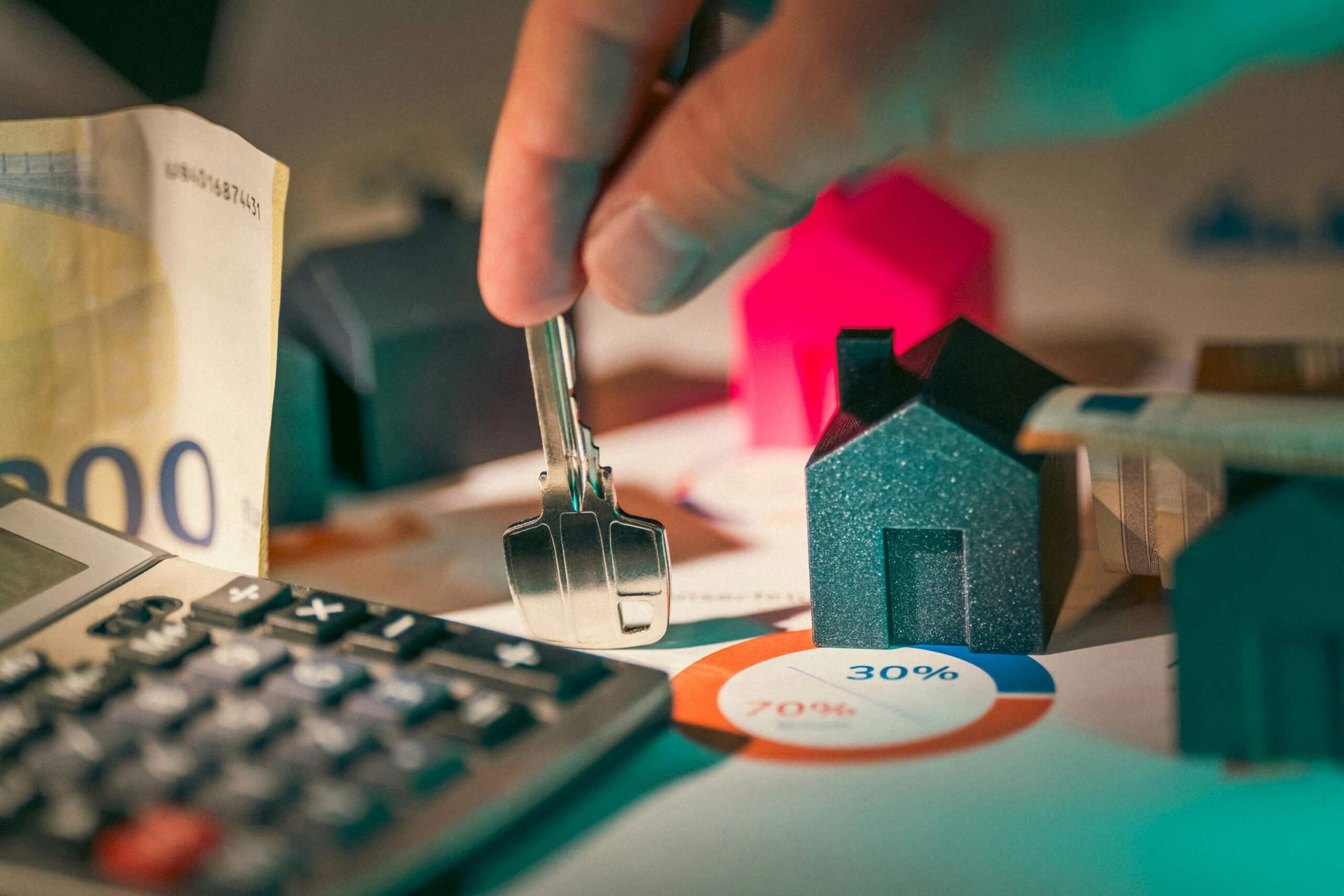 A hand holding a key with a calculator on the table with percent chart for Property Insurance
