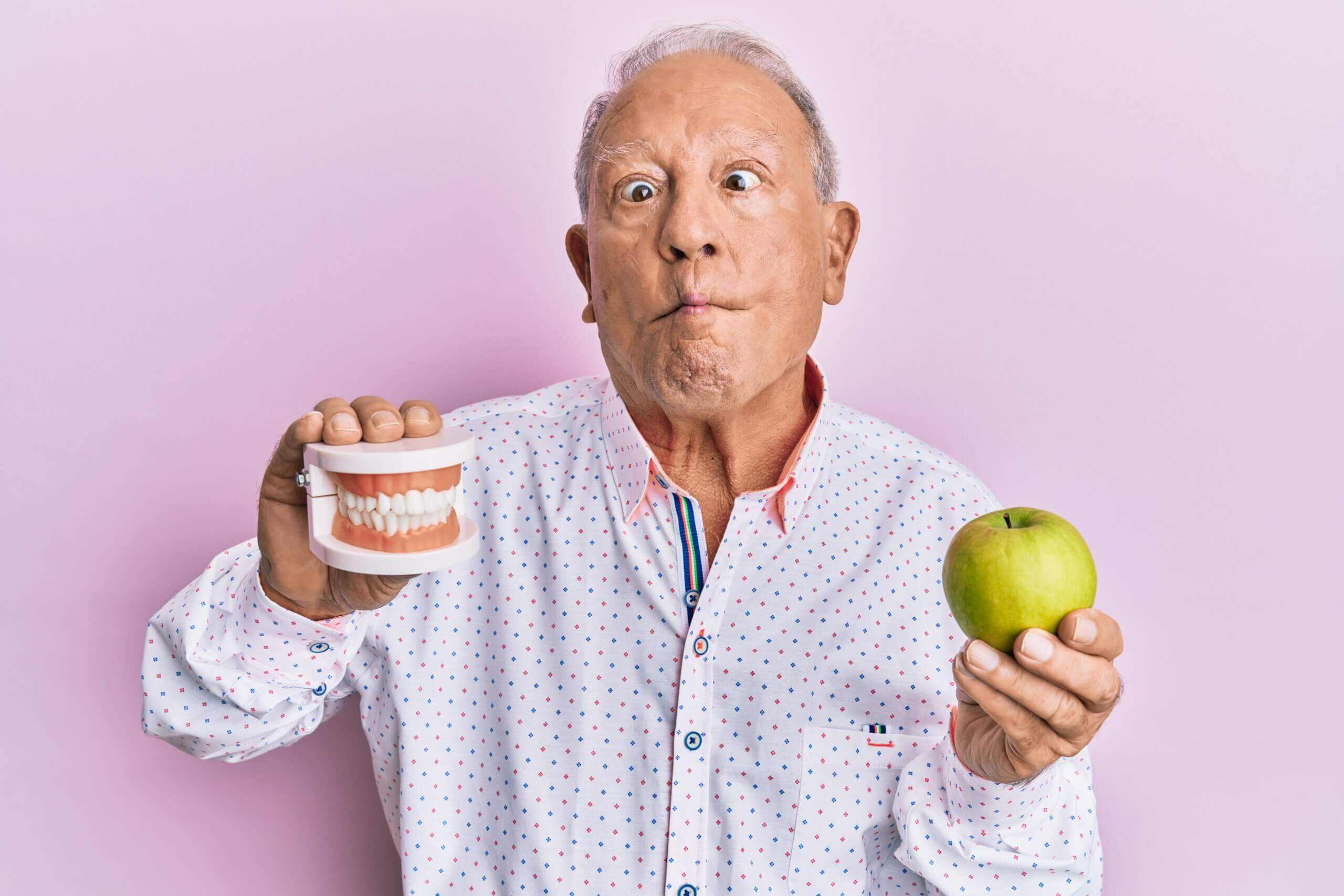A senior citizen man holding a dental teeth